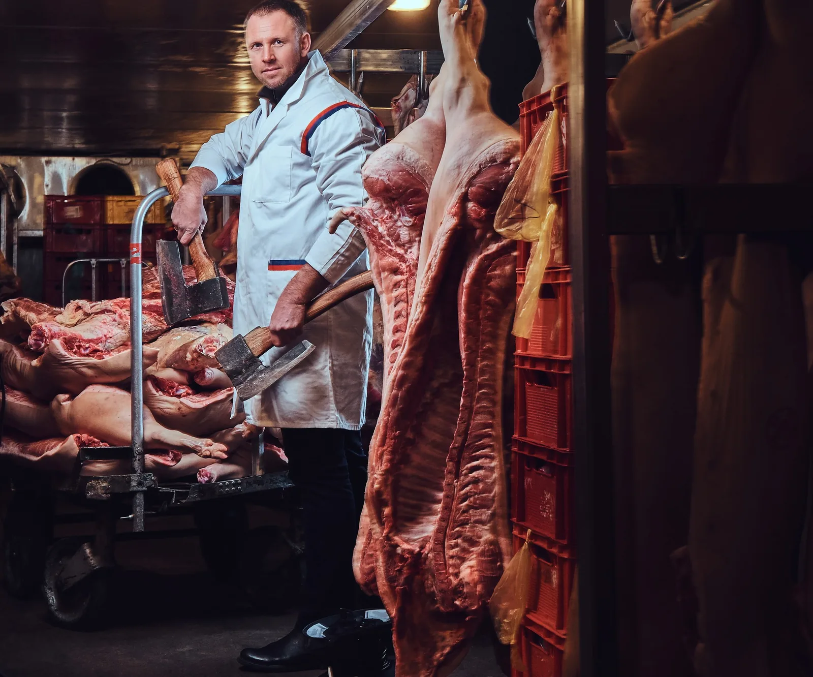 Butcher in white coat holding axes in a cold room, from Vancouver Website Design.