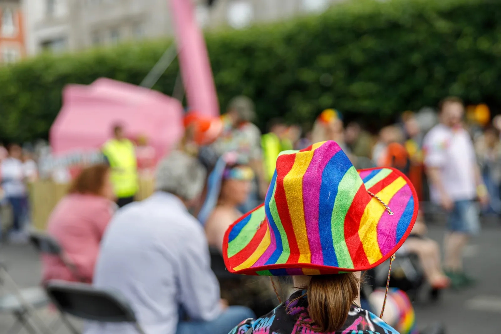 Rear view of person in rainbow hat at lively event, for website design.